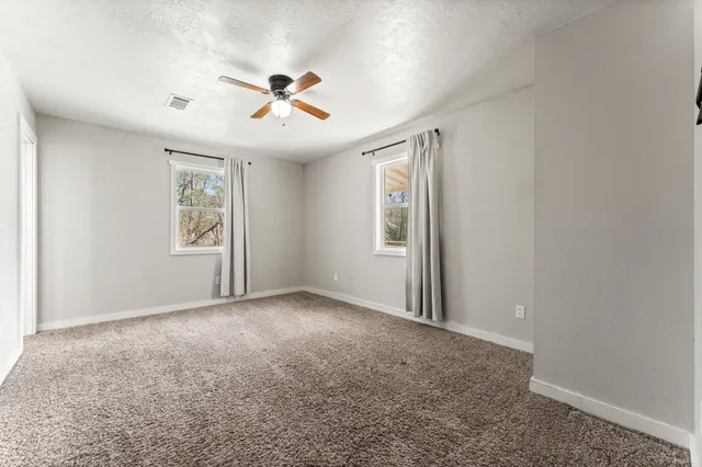 an empty room with windows and fan