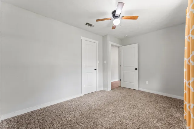 an empty room with a window and a ceiling fan