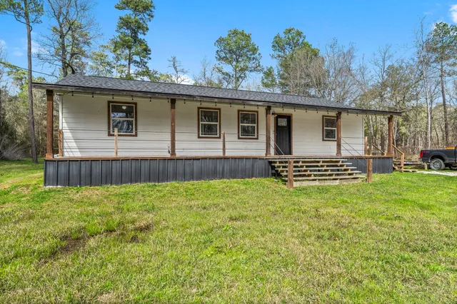 a view of a house with backyard and trees