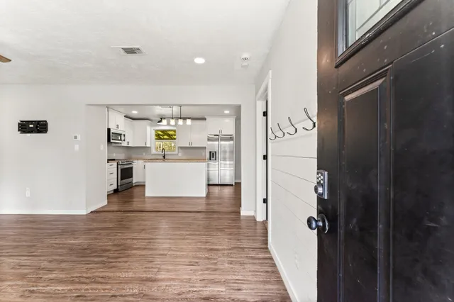 a view of a kitchen with refrigerator and wooden floor