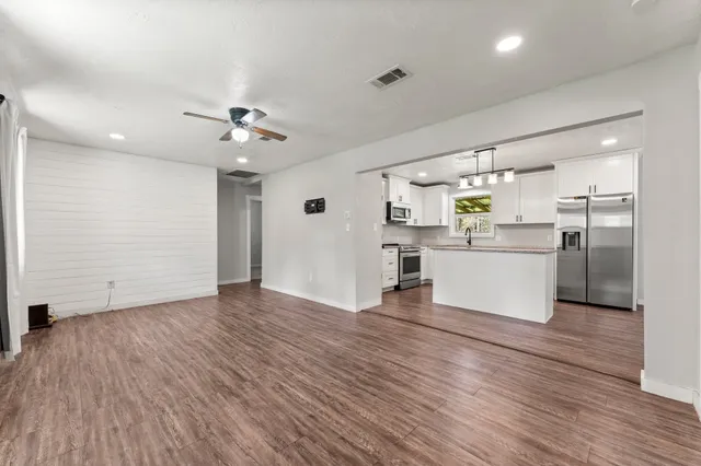a view of kitchen with stainless steel appliances wooden floor and window