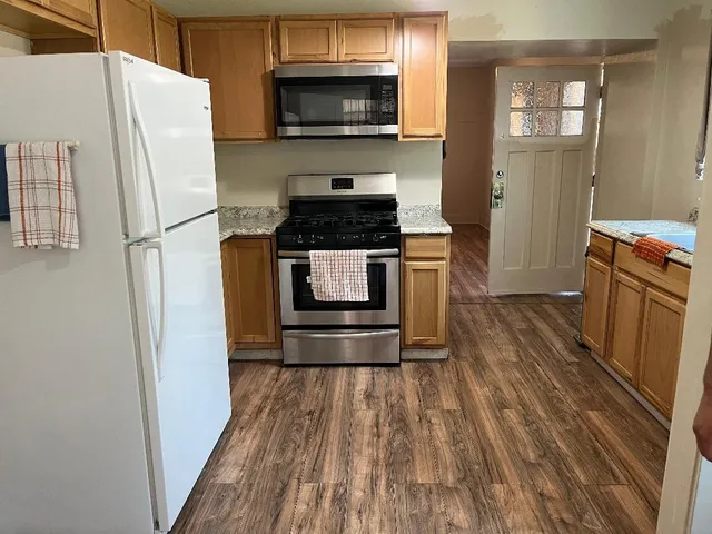 a kitchen with granite countertop a refrigerator and a stove top oven
