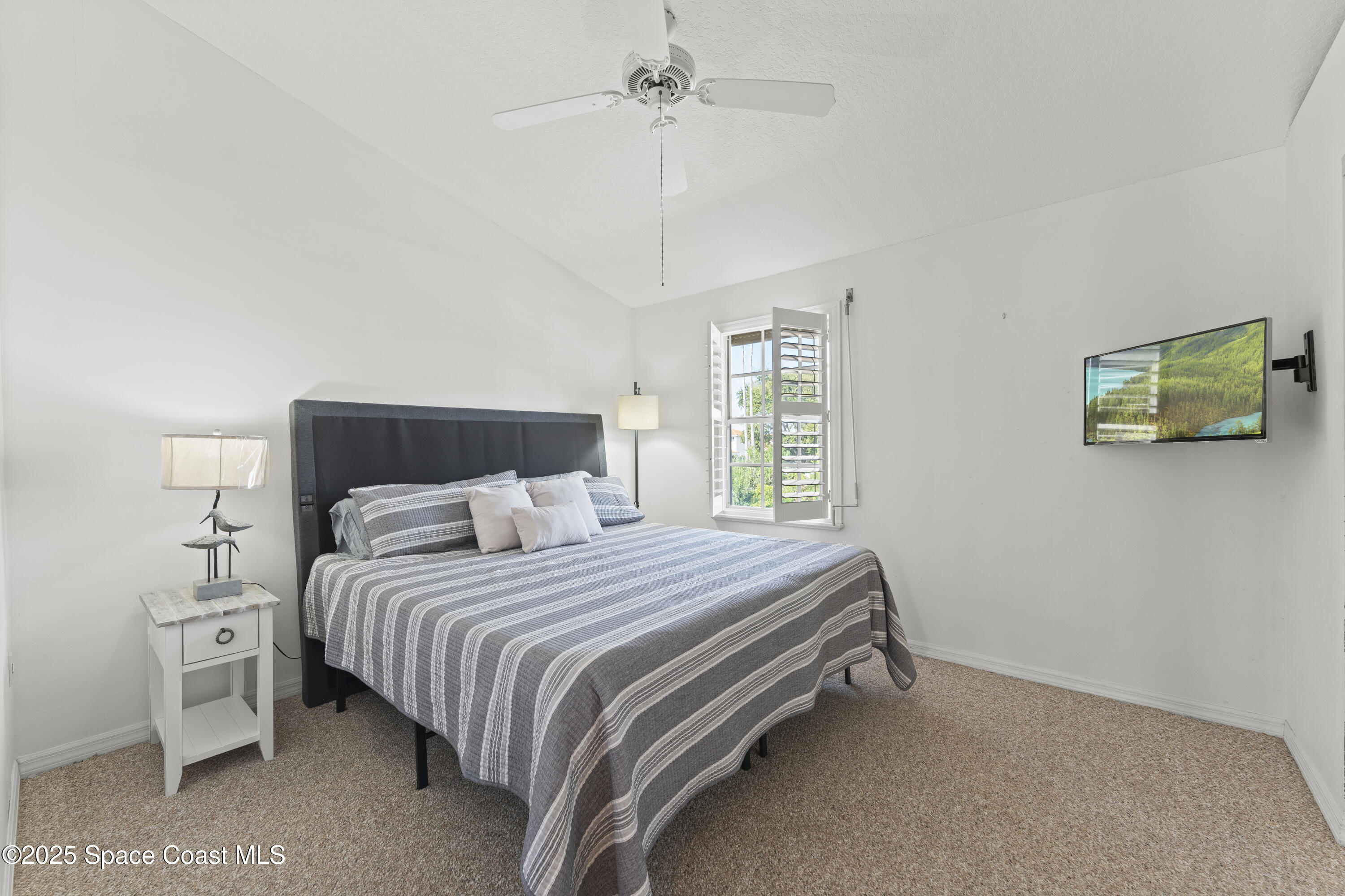 135 Escambia Lane, Unit 204 Cocoa Beach, FL 32931 - Photo 21 of 23 a bedroom with a bed and a chandelier