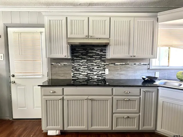 a kitchen with granite countertop a sink window and cabinets