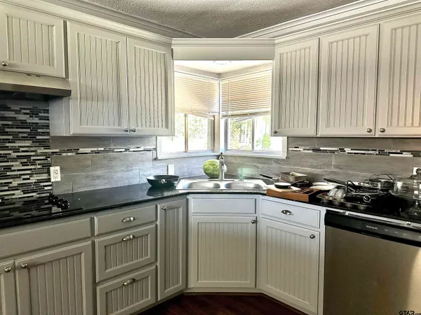 a kitchen with granite countertop cabinets stainless steel appliances a sink and window