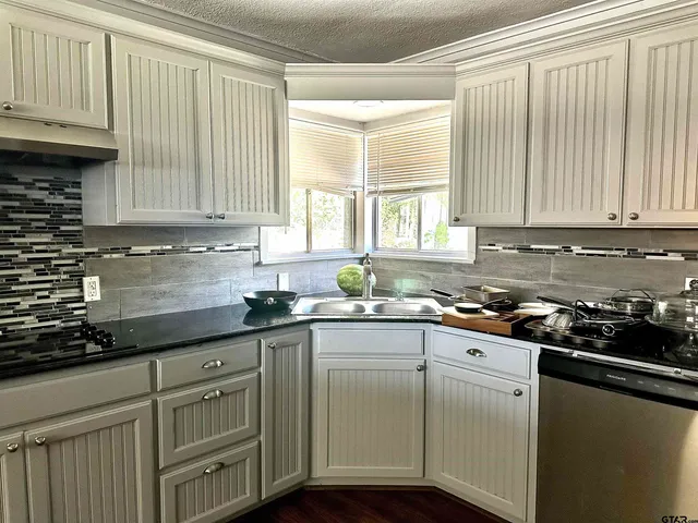 a kitchen with granite countertop cabinets stainless steel appliances a sink and window