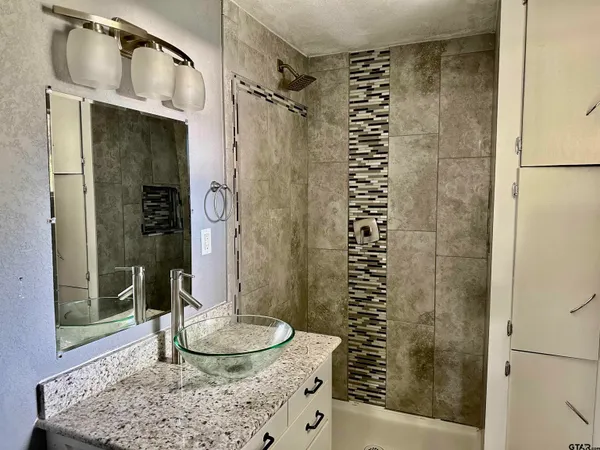 a bathroom with a granite countertop shower a mirror and a sink