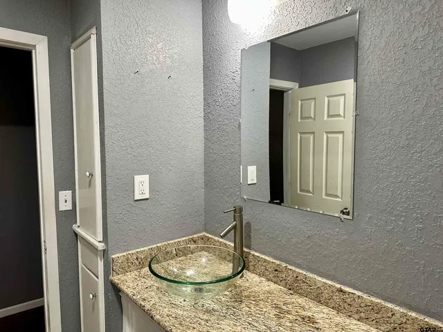 a bathroom with a granite countertop sink and a mirror