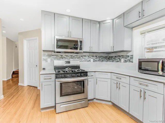 a kitchen with white cabinets stainless steel appliances and wooden floor