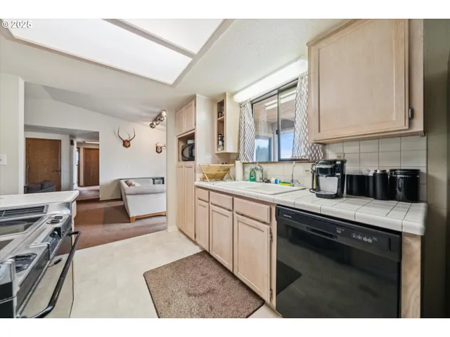 a kitchen with stainless steel appliances granite countertop a stove top oven a sink a counter space and cabinets