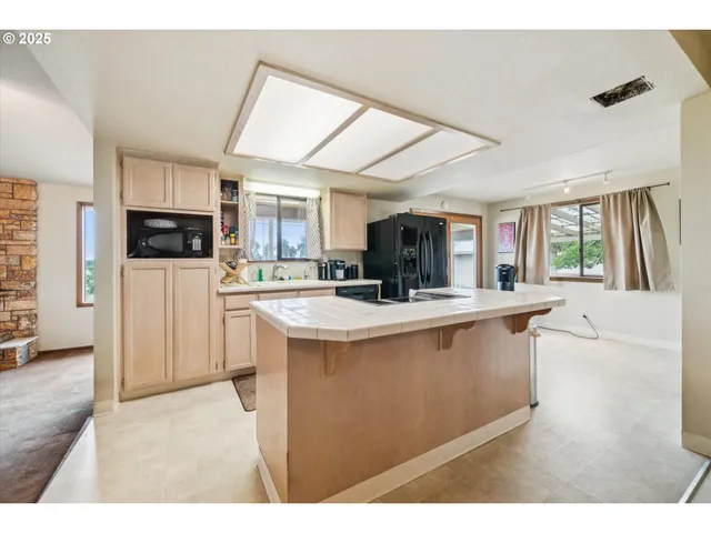 a kitchen with stainless steel appliances granite countertop a stove a sink a refrigerator and white cabinets with wooden floor