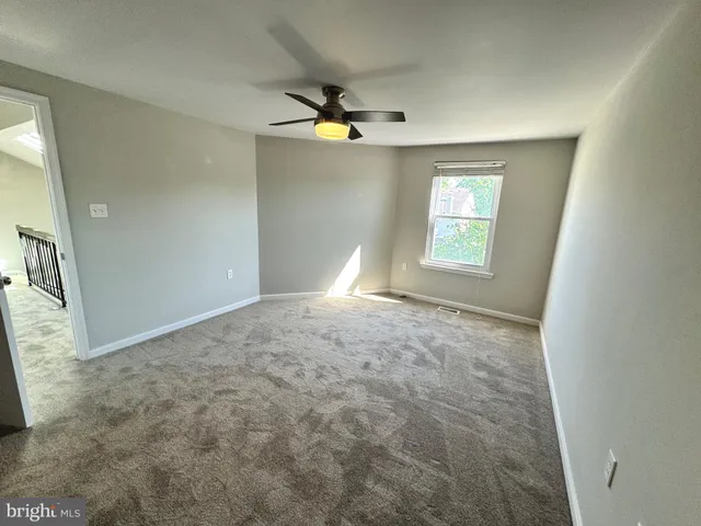 an empty room with a mirror and fan