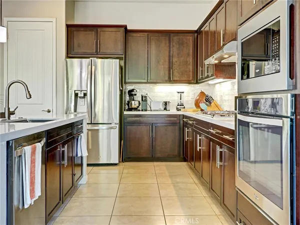 a kitchen with stainless steel appliances granite countertop a refrigerator a stove and a sink with wooden cabinets