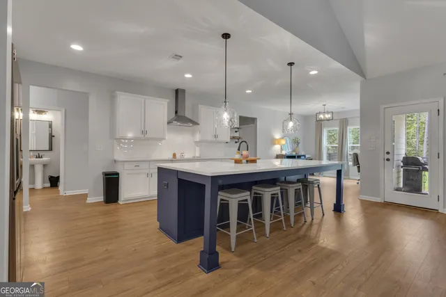 a open kitchen with stainless steel appliances granite countertop a sink dishwasher a stove a refrigerator and a dining table with wooden floor