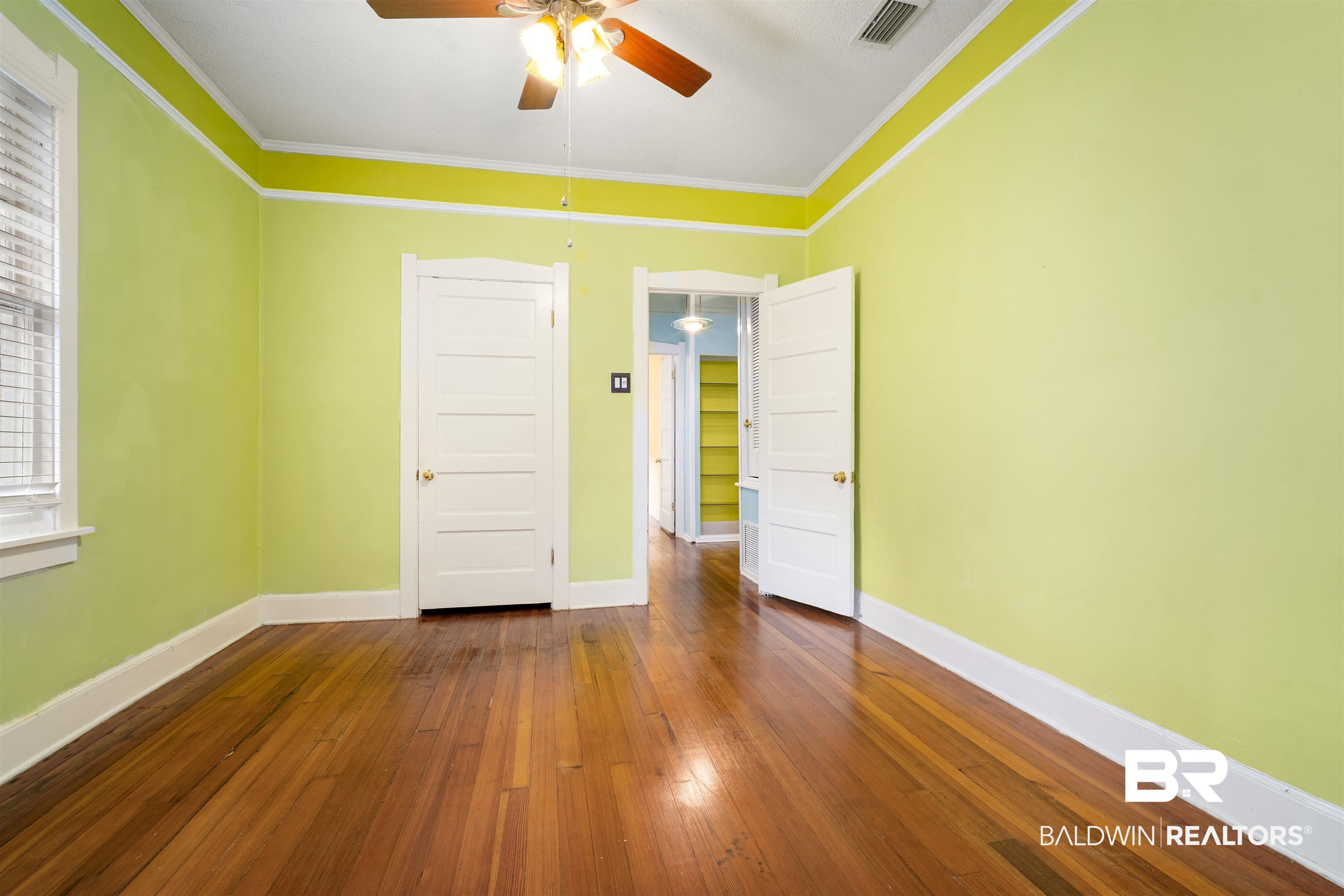 118 Mohawk Street Mobile, AL 36606 - Photo 12 of 26 Unfurnished room with dark wood finished floors, crown molding, and a ceiling fan