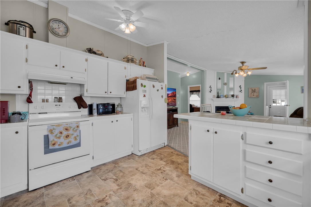 721 Cedar Crest Trail Walhalla, SC 29691 - Photo 13 of 47 A well-equipped kitchen offers ample white cabinetry, a tiled counter, and convenient access to adjacent living spaces.