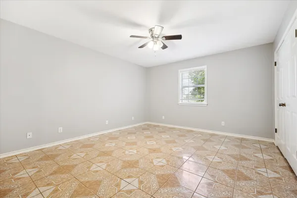 an empty room with a chandelier fan and windows