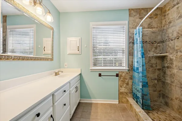 a spacious bathroom with a granite countertop sink and a shower