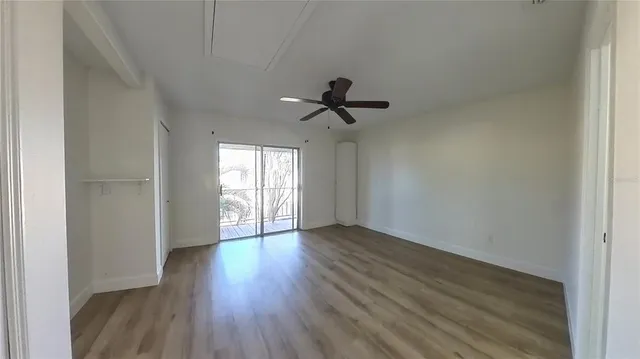 a view of empty room with wooden floor and fan