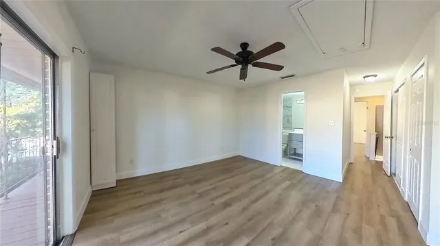 a view of empty room with wooden floor and fan