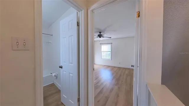 a view of an empty room with wooden floor and a bathroom