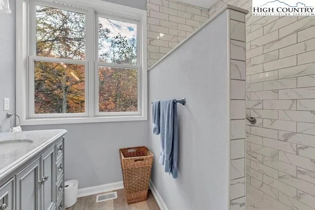 a bathroom with a granite countertop sink a toilet a large mirror and a window