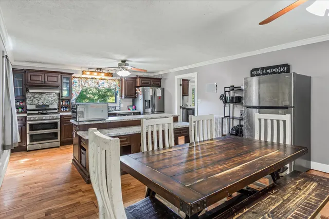 a open kitchen with stainless steel appliances a stove a sink dishwasher and a dining table with wooden floor