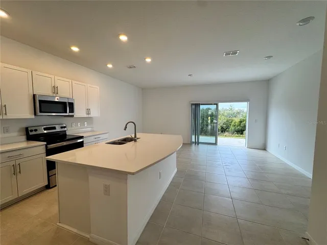 a large kitchen with stainless steel appliances a stove a sink a microwave and cabinets