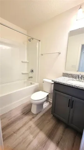 a bathroom with a granite countertop sink toilet mirror vanity and bathtub