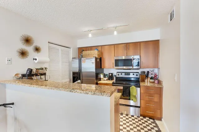 a kitchen with stainless steel appliances kitchen island granite countertop a stove top oven a sink and a granite counter top