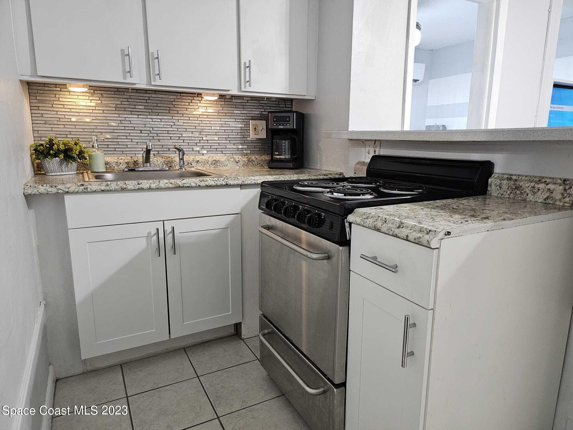 404 Tyler Avenue, Unit 14 Cape Canaveral, FL 32920 - Photo 9 of 29 a kitchen with white cabinets and appliances
