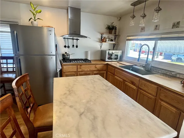 a kitchen with stainless steel appliances granite countertop a refrigerator a sink a stove and white cabinets