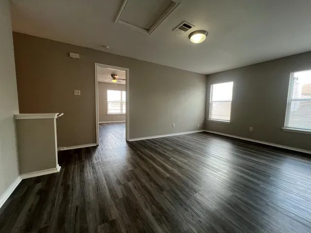 an empty room with wooden floor and windows