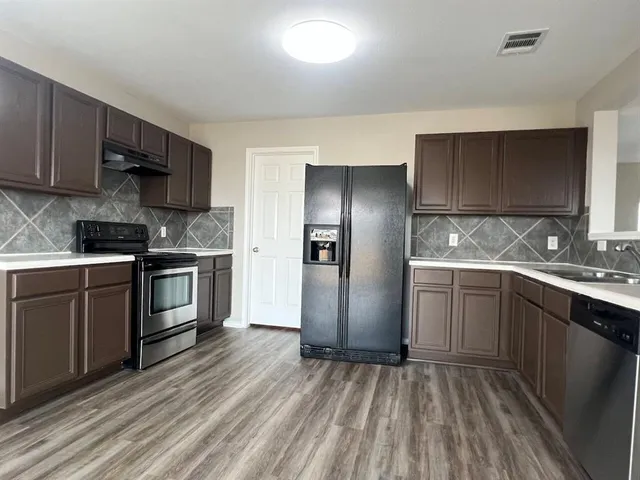 a kitchen with stainless steel appliances granite countertop a refrigerator a sink dishwasher a stove and a refrigerator