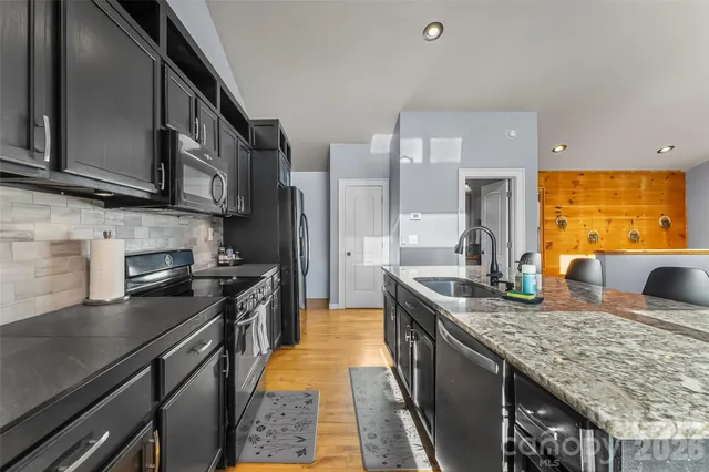 a kitchen with stainless steel appliances granite countertop a sink stove and refrigerator