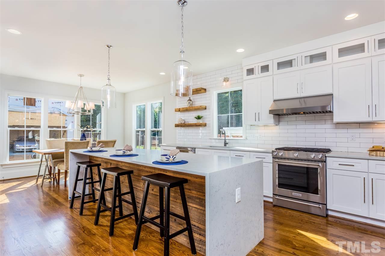 3203.5 Clark Avenue Raleigh, NC 27607 - Photo 8 of 25 a kitchen with a stove a refrigerator and a dining table with wooden floor