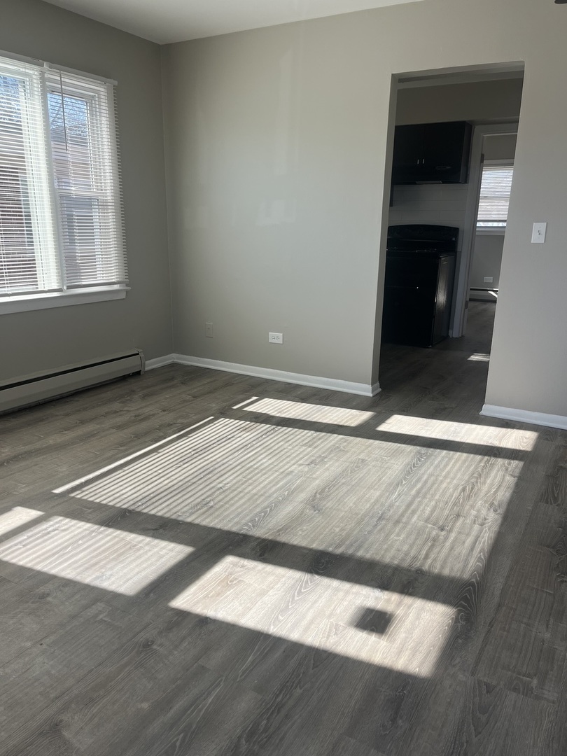 1340 North Main Street, Unit E4 Wheaton, IL 60187 - Photo 2 of 7 an empty room with wooden floor and windows