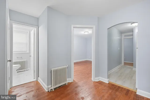 a view of a hallway with wooden floor and a bathroom