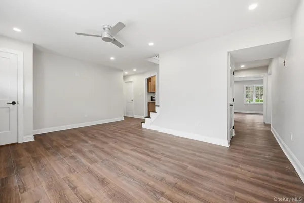 a view of an empty room with wooden floor and a ceiling fan