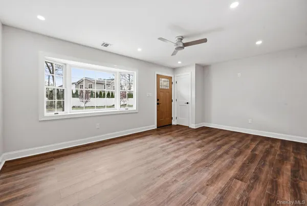 a view of an empty room with a window and wooden floor
