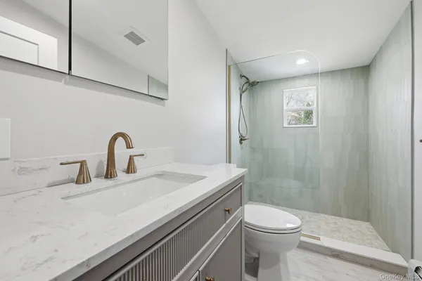 a bathroom with a sink a toilet and shower