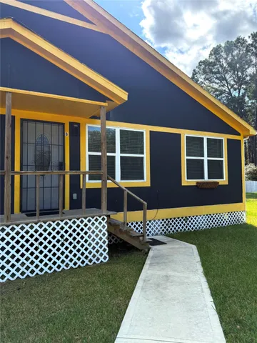 a side view of a house with a barbeque and wooden bench