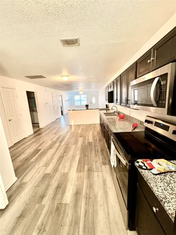 a view of a kitchen with wooden floor and electronic appliances