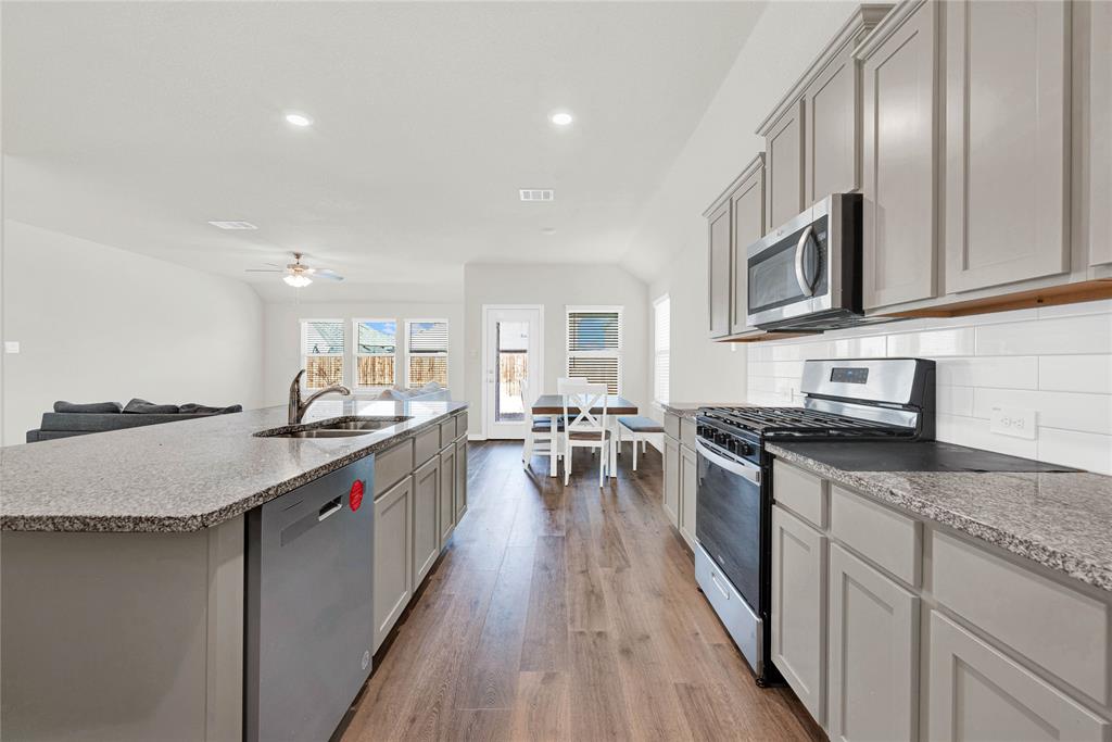 9713 Quail Pointe Road Aubrey, TX 76227 - Photo 10 of 23 Kitchen featuring stainless steel appliances, light wood-style floors, light stone countertops, backsplash, and recessed lighting