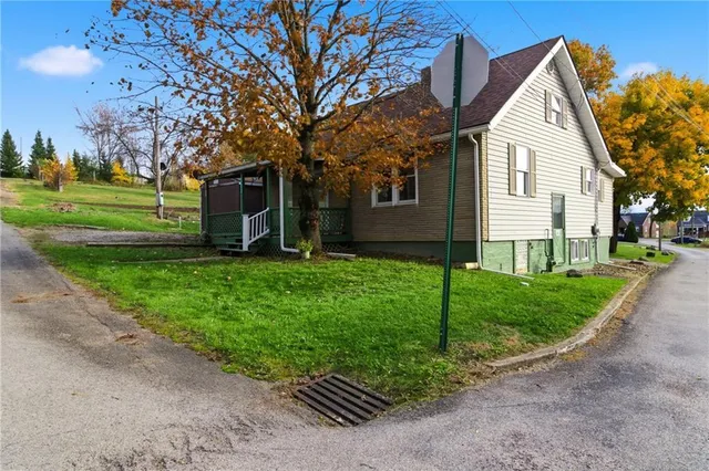 a view of a white house with a yard and large tree