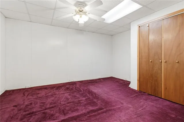 an empty room with a chandelier fan and windows