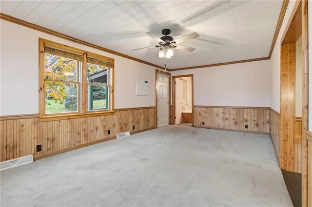 an empty room with chandelier fan and windows
