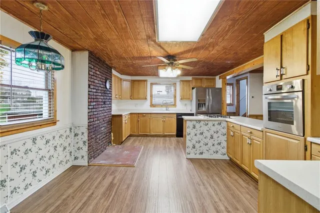 a kitchen with granite countertop a sink cabinets stainless steel appliances and a large window