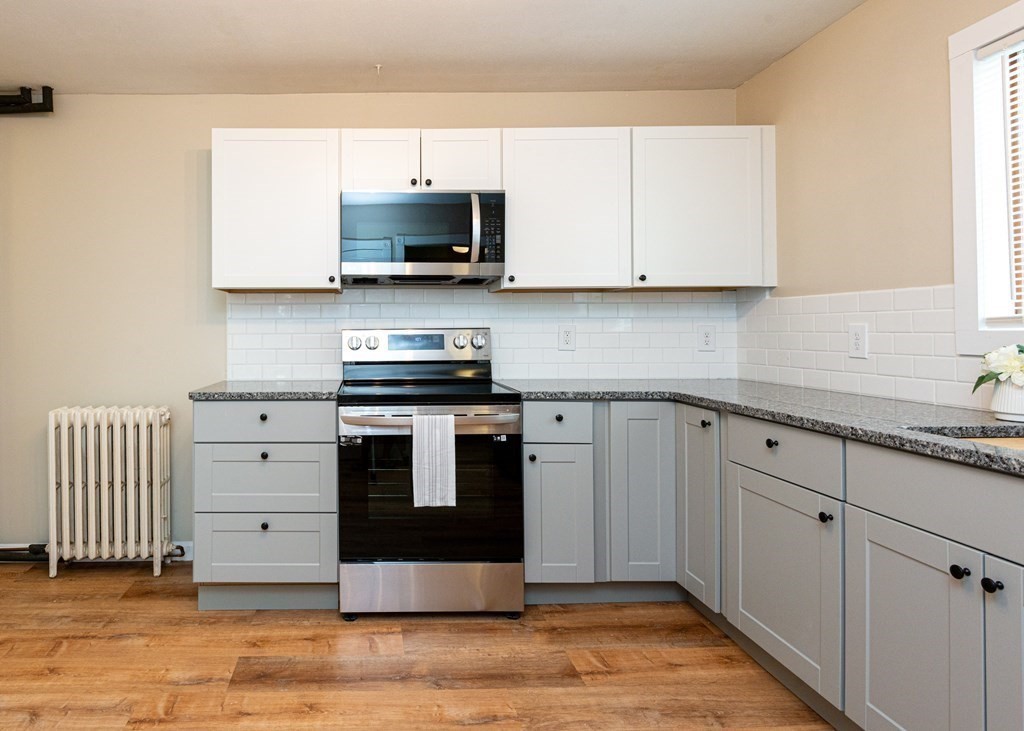 13 Melville Place Lynn, MA 01902 - Photo 7 of 41 a kitchen with white cabinets and stainless steel appliances