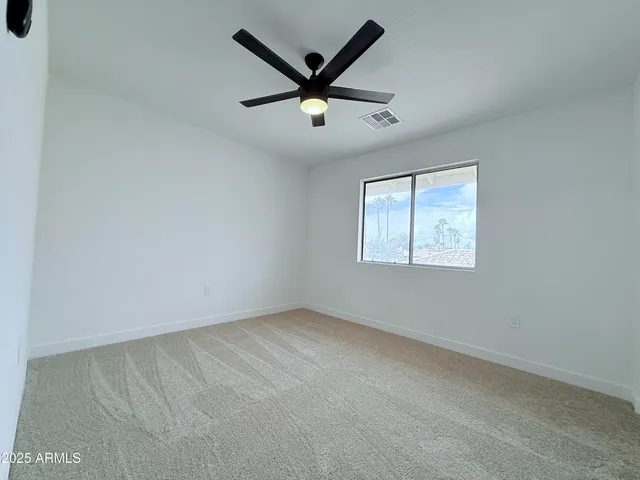 an empty room with ceiling fan and window